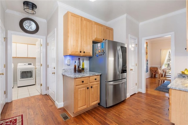 kitchen with visible vents, stainless steel refrigerator with ice dispenser, hardwood / wood-style flooring, washer / clothes dryer, and crown molding