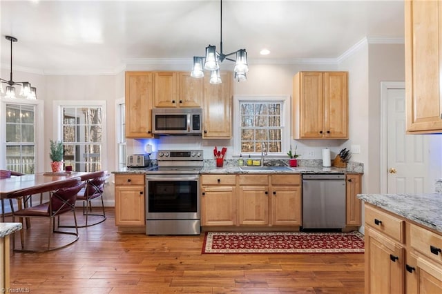 kitchen featuring appliances with stainless steel finishes, wood finished floors, crown molding, and a sink