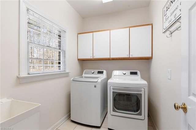 clothes washing area with washer and dryer, baseboards, cabinet space, and light tile patterned floors