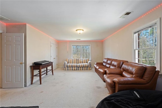 living area featuring visible vents, baseboards, carpet, and crown molding