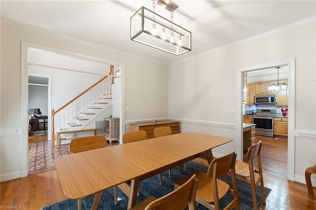 dining room featuring a notable chandelier, stairway, crown molding, and light wood-style floors