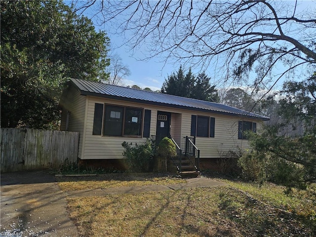 ranch-style house featuring metal roof and fence