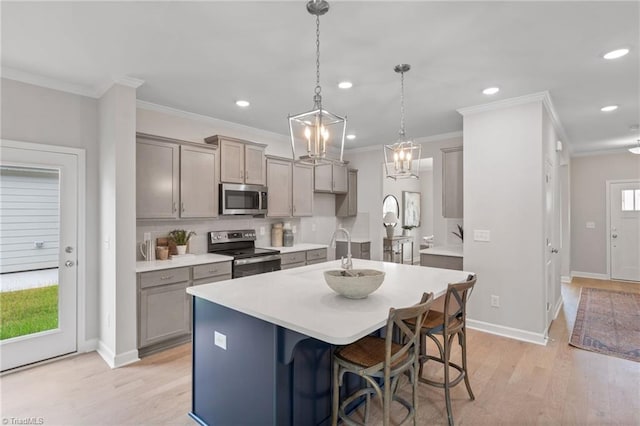 kitchen with light countertops, appliances with stainless steel finishes, backsplash, gray cabinets, and light wood finished floors