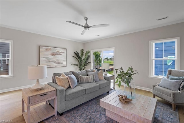 living room featuring visible vents, ornamental molding, ceiling fan, wood finished floors, and baseboards