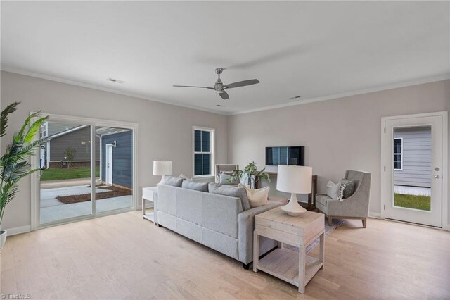 living area with ornamental molding, visible vents, ceiling fan, and light wood finished floors