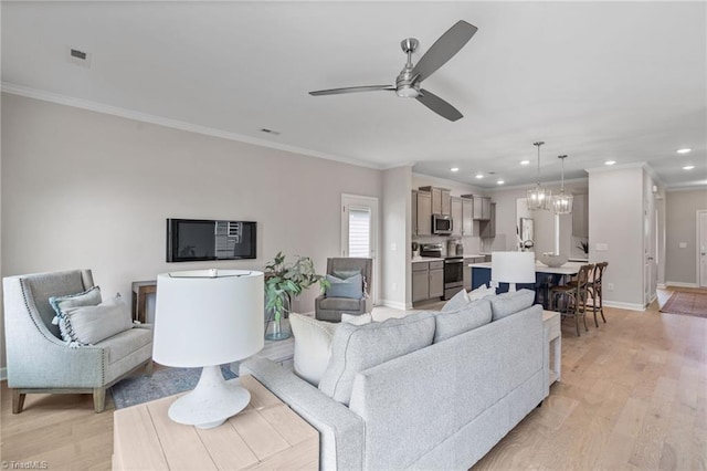 living room with recessed lighting, light wood-style floors, ornamental molding, baseboards, and ceiling fan with notable chandelier