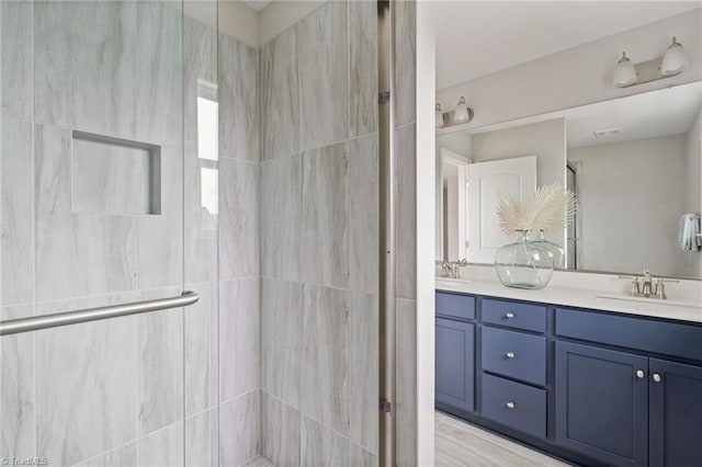 full bath featuring a stall shower, a sink, and double vanity