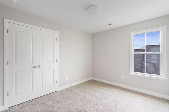 unfurnished bedroom with a closet, carpet flooring, visible vents, and baseboards