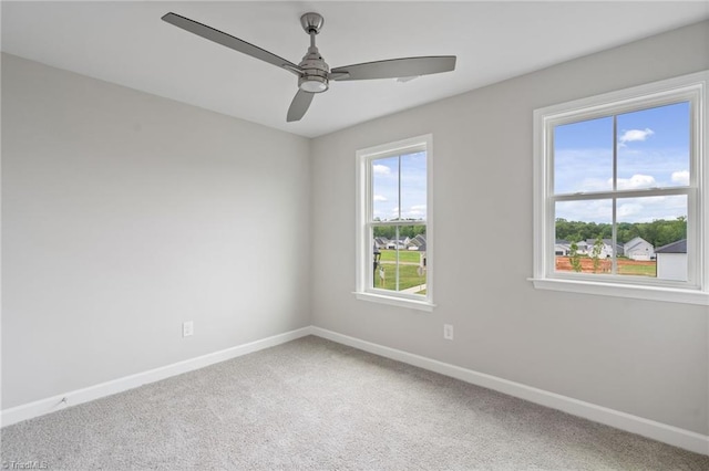 carpeted empty room featuring ceiling fan and baseboards