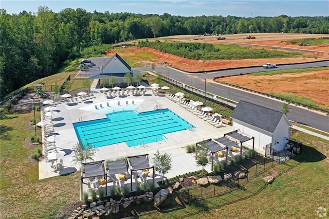 pool with a patio area, fence, and a wooded view