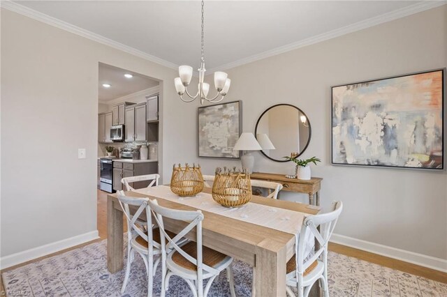 dining area featuring crown molding, a notable chandelier, light wood-style flooring, and baseboards