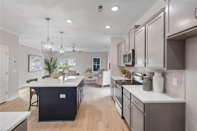 kitchen featuring crown molding, tasteful backsplash, visible vents, appliances with stainless steel finishes, and a kitchen island with sink