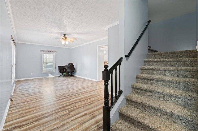 stairway featuring crown molding, wood-type flooring, a textured ceiling, and ceiling fan