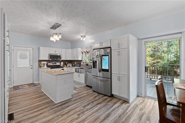 kitchen with white cabinets, a chandelier, light wood-style flooring, a center island, and stainless steel appliances