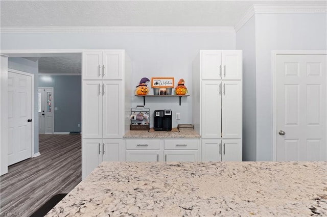 interior space with white cabinets, crown molding, light stone counters, and wood finished floors