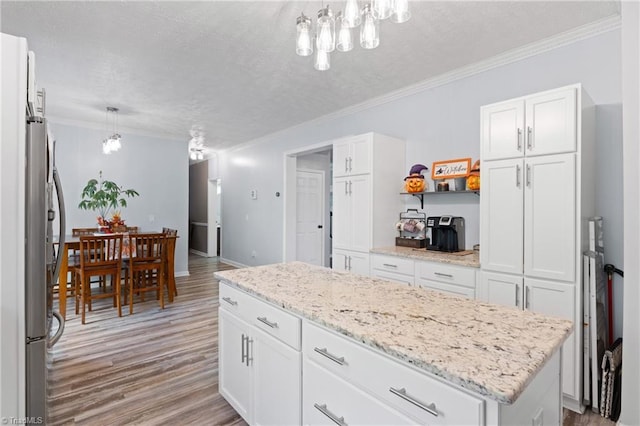 kitchen featuring crown molding, a textured ceiling, light wood-style flooring, and white cabinets