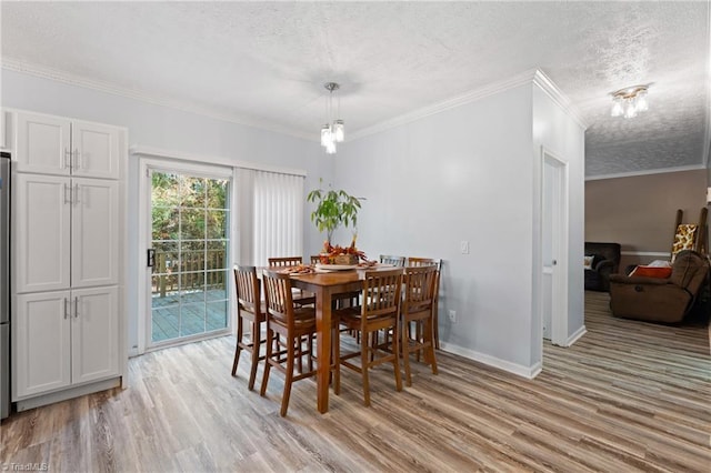 dining room featuring ornamental molding, a textured ceiling, and light wood-type flooring