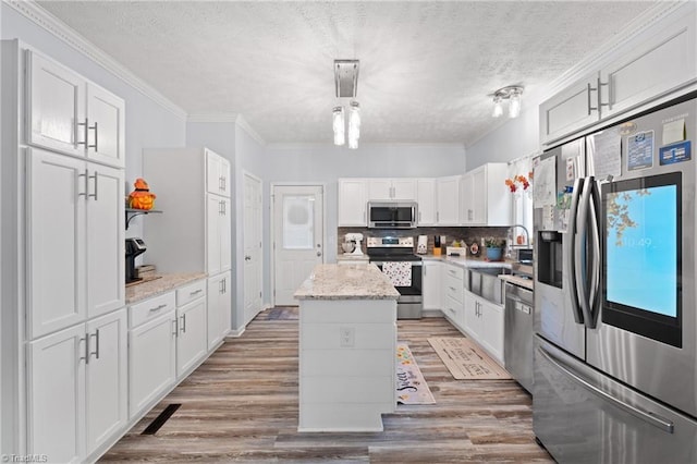 kitchen with a kitchen island, appliances with stainless steel finishes, light hardwood / wood-style flooring, and white cabinetry