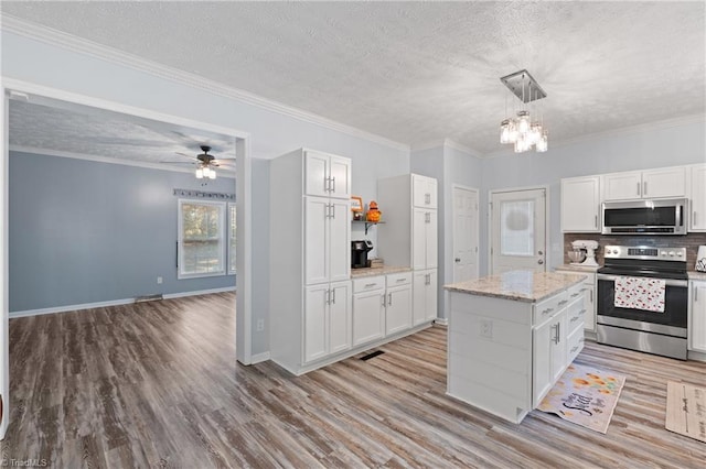 kitchen with hanging light fixtures, appliances with stainless steel finishes, light hardwood / wood-style flooring, and white cabinets