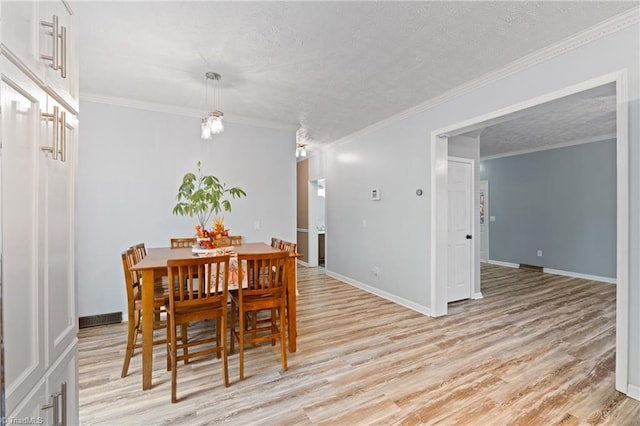 dining space featuring light hardwood / wood-style flooring, a textured ceiling, and crown molding