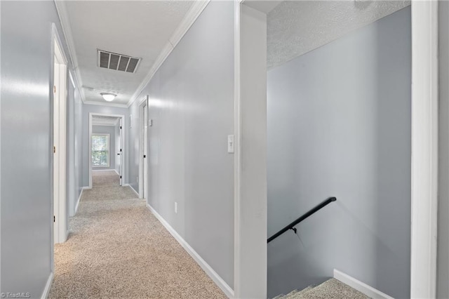 corridor with crown molding, carpet, baseboards, an upstairs landing, and visible vents