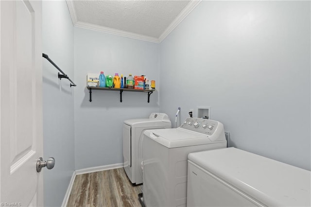 clothes washing area featuring hardwood / wood-style floors, crown molding, a textured ceiling, and separate washer and dryer