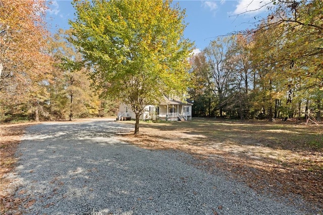 obstructed view of property with a porch and gravel driveway