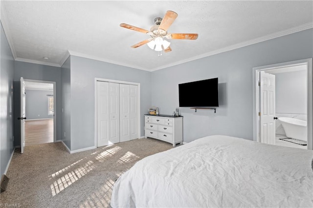 carpeted bedroom featuring crown molding, a closet, ensuite bathroom, and ceiling fan