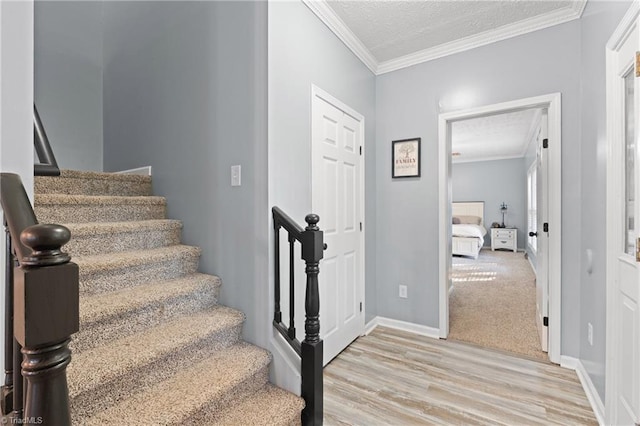 stairs featuring ornamental molding, hardwood / wood-style flooring, and a textured ceiling