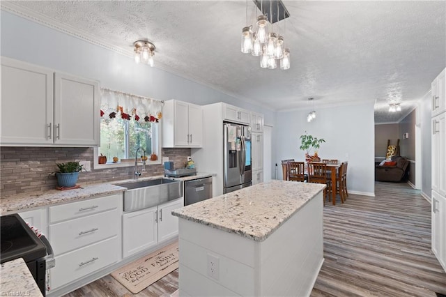 kitchen with a sink, appliances with stainless steel finishes, crown molding, and a textured ceiling