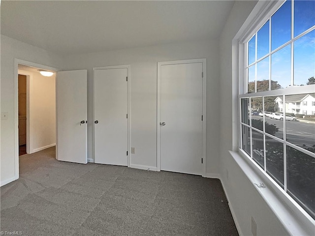 unfurnished bedroom featuring two closets and carpet