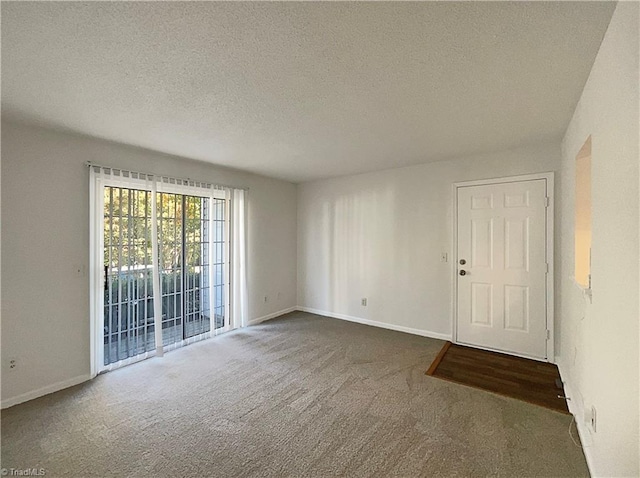 spare room with dark carpet and a textured ceiling