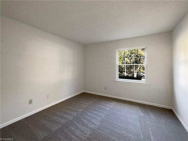 unfurnished room featuring a textured ceiling and dark carpet