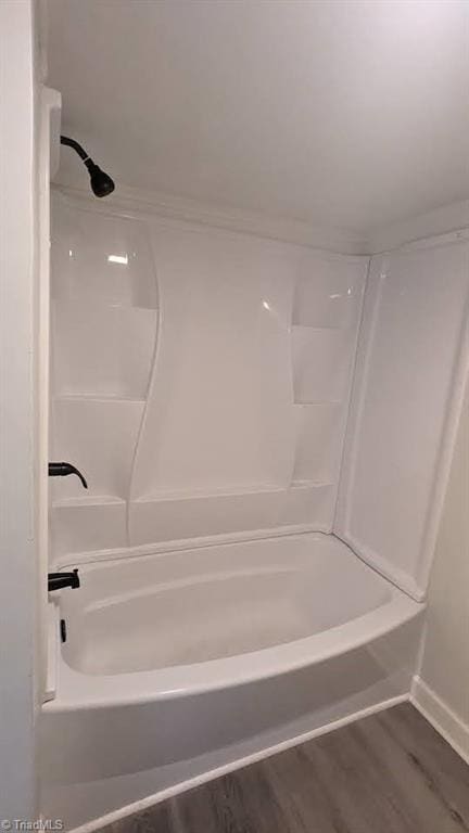 bathroom featuring hardwood / wood-style floors and washtub / shower combination