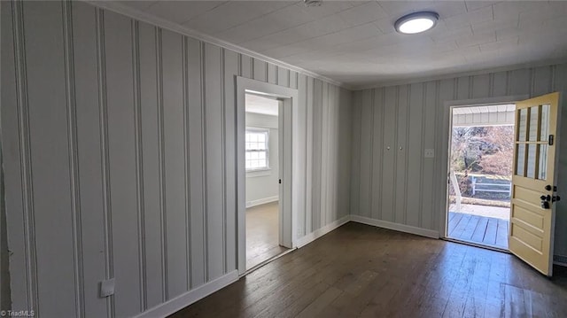 empty room with a healthy amount of sunlight, crown molding, and dark wood-type flooring