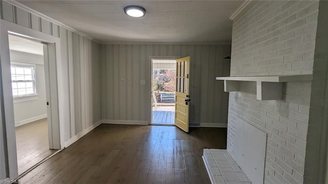 entryway featuring ornamental molding, a brick fireplace, and dark wood-type flooring