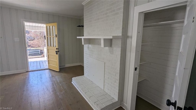 interior space featuring wooden walls, hardwood / wood-style flooring, a fireplace, and crown molding