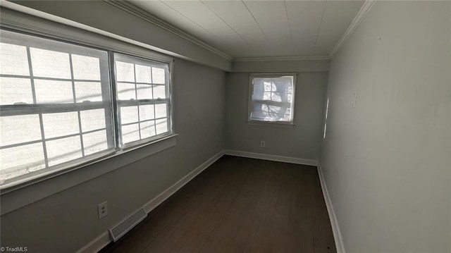 spare room with crown molding, dark wood-type flooring, and a wealth of natural light