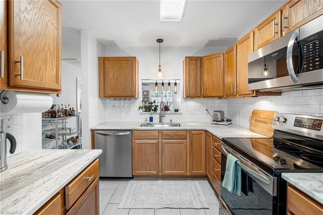 3719 Spanish Peak Dr, High Point, NC 27265 - kitchen featuring appliances with stainless steel finishes, a sink, tasteful backsplash, light stone countertops, and decorative light fixtures