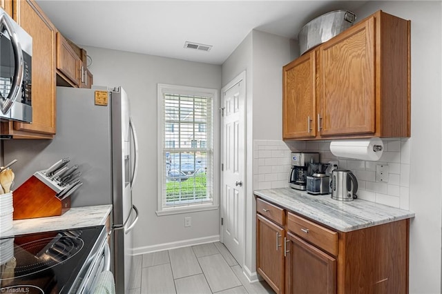 3719 Spanish Peak Dr, High Point, NC 27265 - kitchen featuring stainless steel microwave, decorative backsplash, baseboards, and brown cabinetry