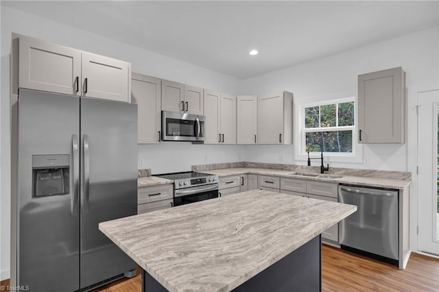 kitchen featuring stainless steel appliances, light hardwood / wood-style floors, sink, a center island, and gray cabinetry