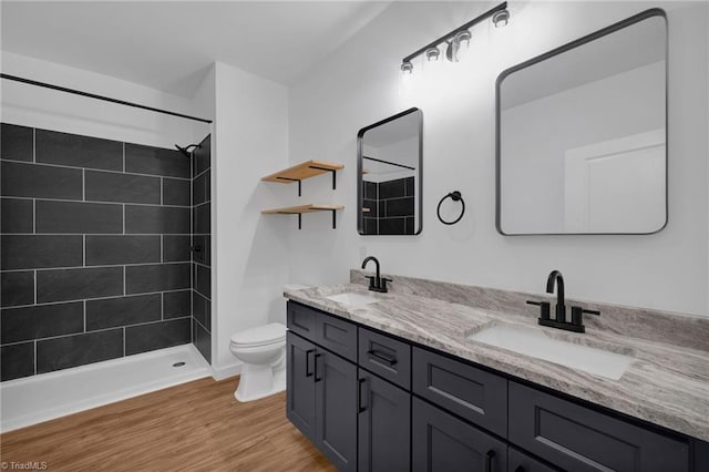 bathroom with a tile shower, wood-type flooring, toilet, and vanity