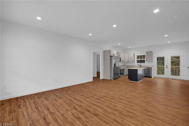 unfurnished living room with sink, french doors, and light hardwood / wood-style floors