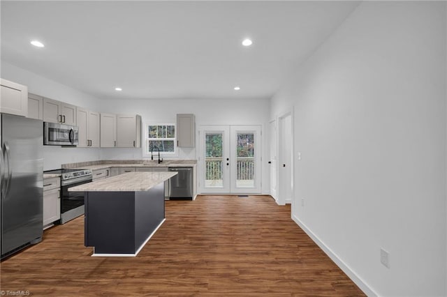 kitchen with dark wood-type flooring, gray cabinetry, appliances with stainless steel finishes, and a center island