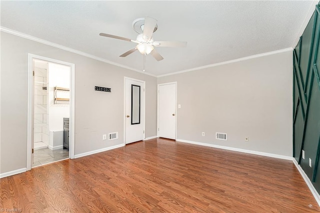 unfurnished bedroom featuring wood finished floors, ornamental molding, baseboards, ensuite bathroom, and a ceiling fan