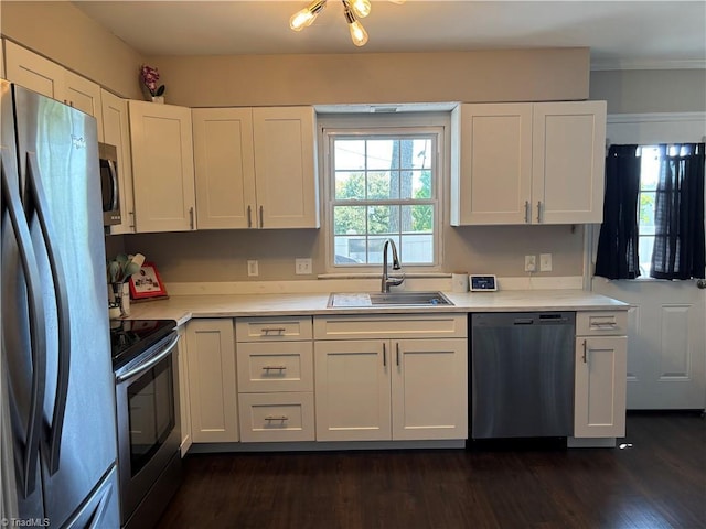 kitchen featuring stainless steel appliances, a sink, white cabinetry, light countertops, and dark wood finished floors