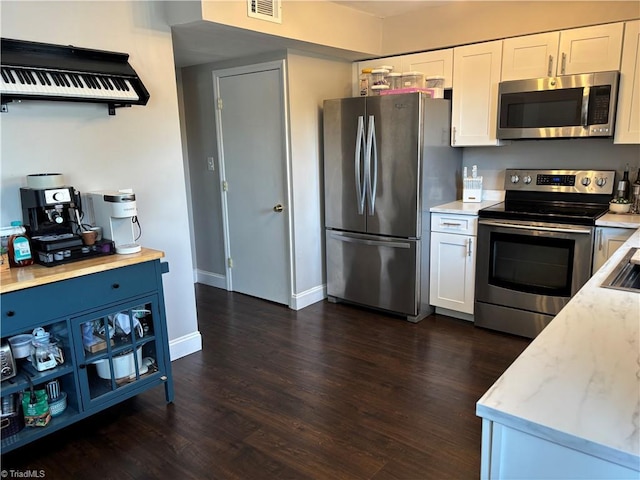 kitchen featuring appliances with stainless steel finishes, white cabinetry, dark wood-style floors, and baseboards