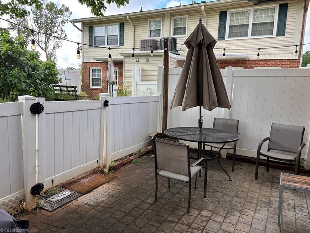 view of patio / terrace with outdoor dining space, a fenced backyard, and central AC unit