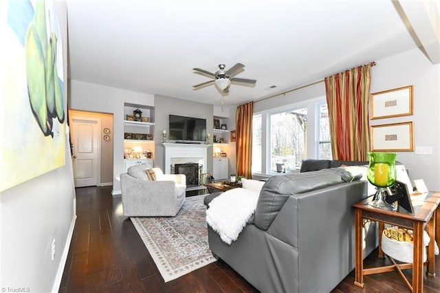 living room with dark wood-type flooring, built in features, and ceiling fan