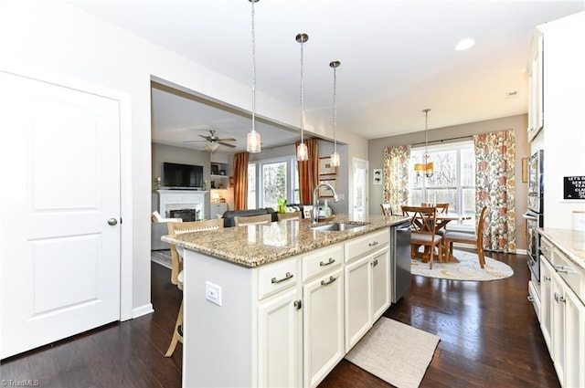 kitchen with a kitchen bar, sink, appliances with stainless steel finishes, pendant lighting, and a kitchen island with sink